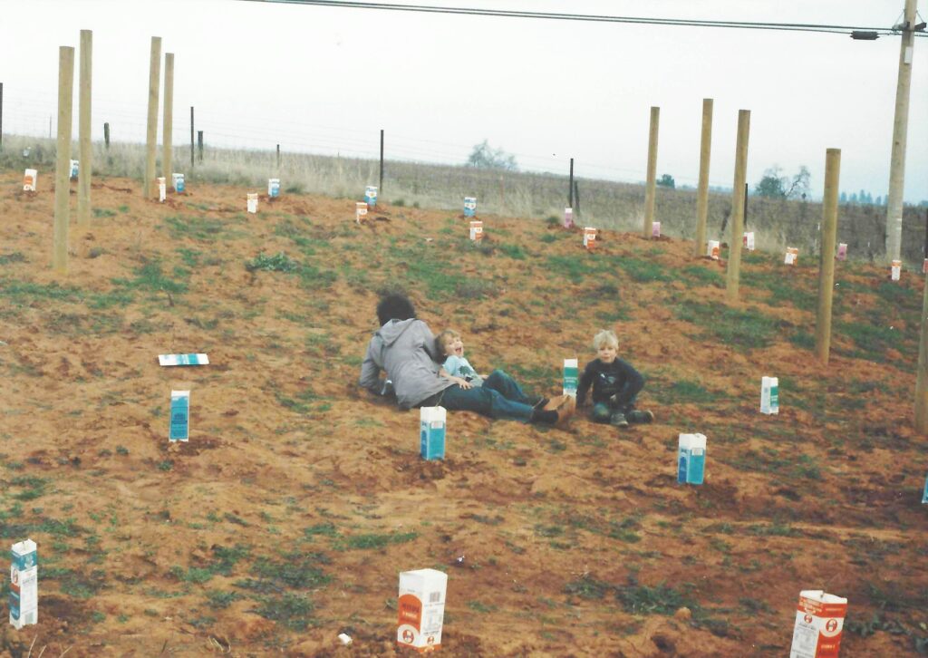 Suzy planting our first vines with the kids.